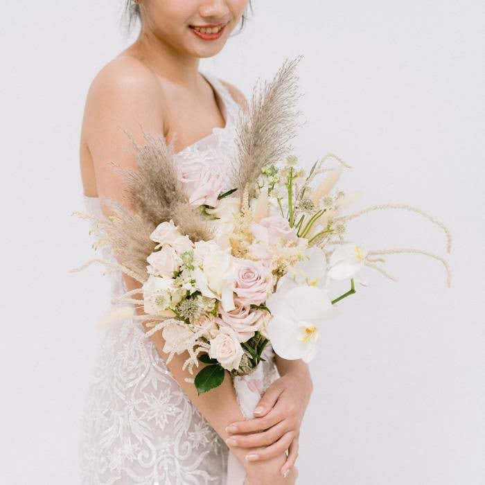 a bridal is holding a pampas grass blush roses orchid bouquet